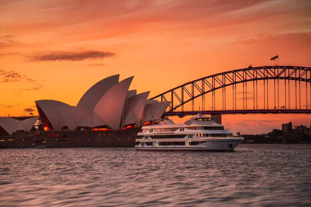 A Dinner Cruise ship sailing past the Sydney Opera House and Harbour Bridge at Sunset